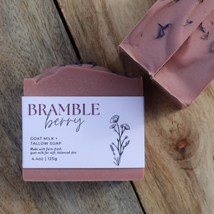 Goat milk soap bar with 'Bramble Berry' packaging on a wooden surface