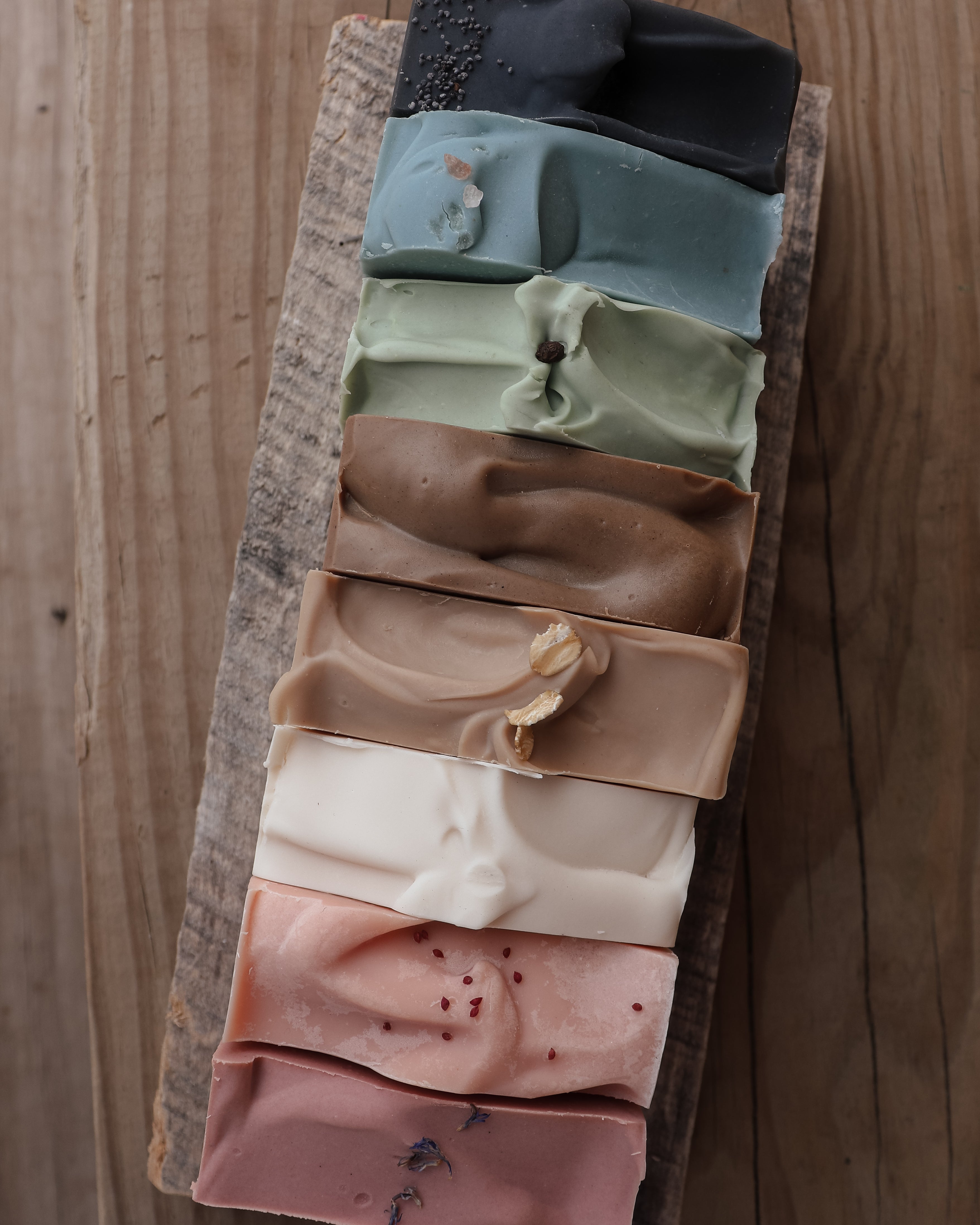 Set of colorful soap bars arranged in a wooden tray on a wooden surface