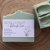 Bar of Bergamot + Black Tea soap with a label on a wooden surface