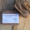 Two bars of sandalwood vanilla soap on a wooden surface with a label.